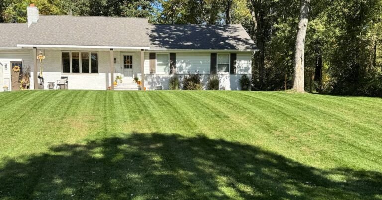 Residential lawn showing fresh mowing stripes in front of a ranch house